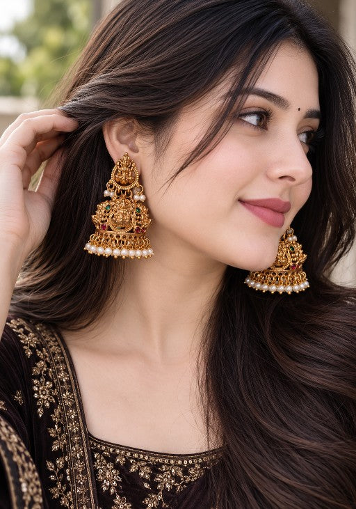 Divya Lakshmi gold-tone temple jhumka earrings with green and ruby-red stones and pearl drops worn by a woman