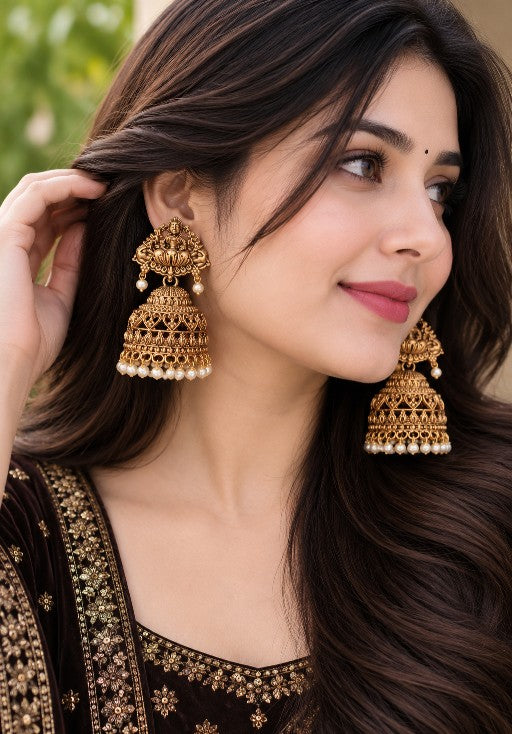 Divya Lakshmi gold-tone temple jhumka earrings with Goddess Lakshmi design and pearl drops worn by a woman