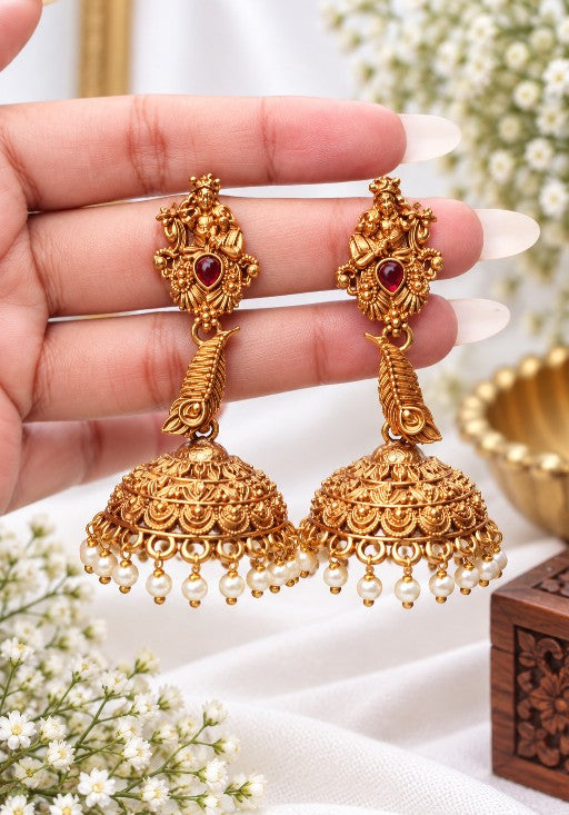 Detailed Radha Krishna and peacock feather jhumka with gold tone finish, ruby stone and pearl drops