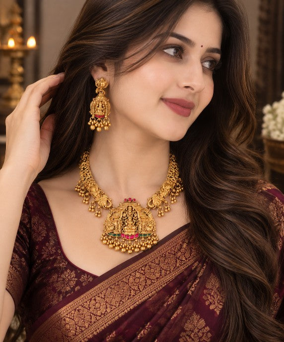 South Indian Lakshmi bridal necklace set with heavy temple jewellery design, gold tone finish and traditional green and ruby red stone detailing