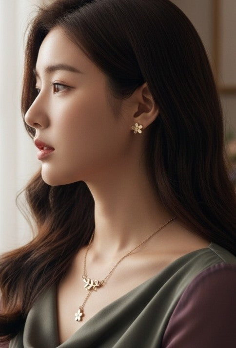Tavisi Amara gold leaf charm necklace and matching earrings set worn by a woman