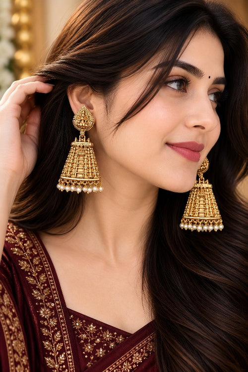 Woman wearing Aadhira premium brass Lakshmi temple jhumka earrings with pearl drops