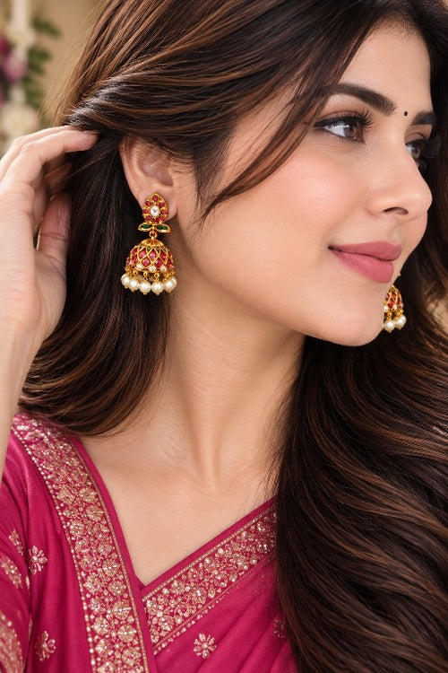 Woman wearing Aaradhya premium brass floral pearl jhumka earrings with pink green stones and pearl drops