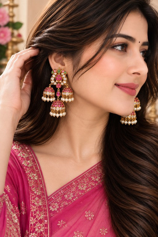 Woman wearing Aaradhya premium brass Kemp pearl jhumka earrings with pink green detailing and pearl drops