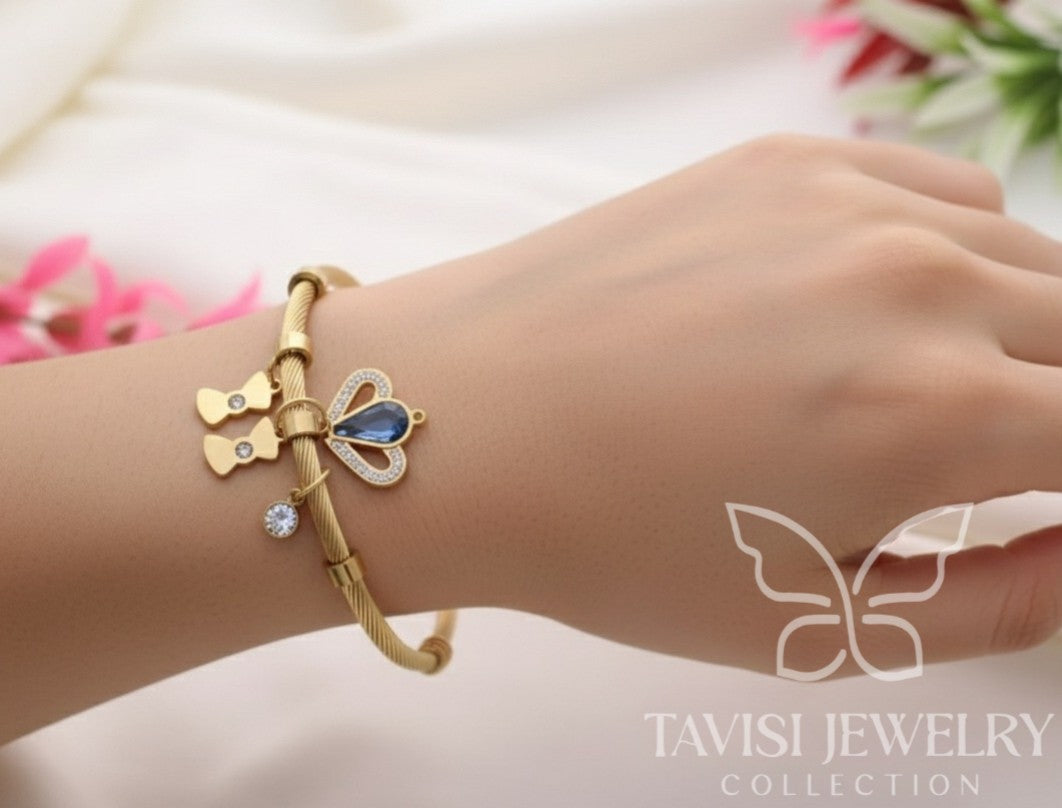 Detailed view of Tavisi Celeste Blue Charm Bracelet showcasing anti-tarnish stainless steel, butterfly charms and blue crystal centrepiece.