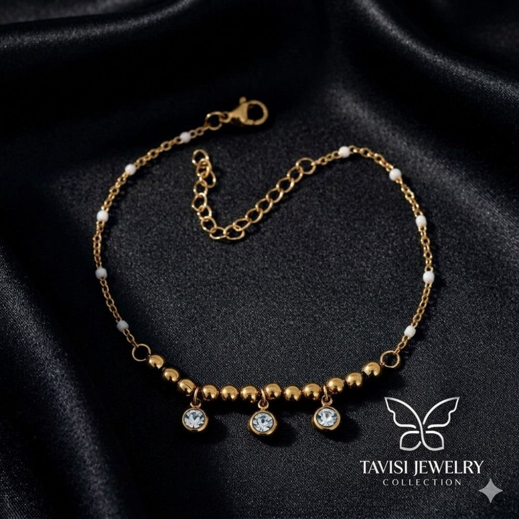 Gold Bead CZ Drop Charm Bracelet with triple crystal drops on white fabric - Tavisi Jewelry Collection