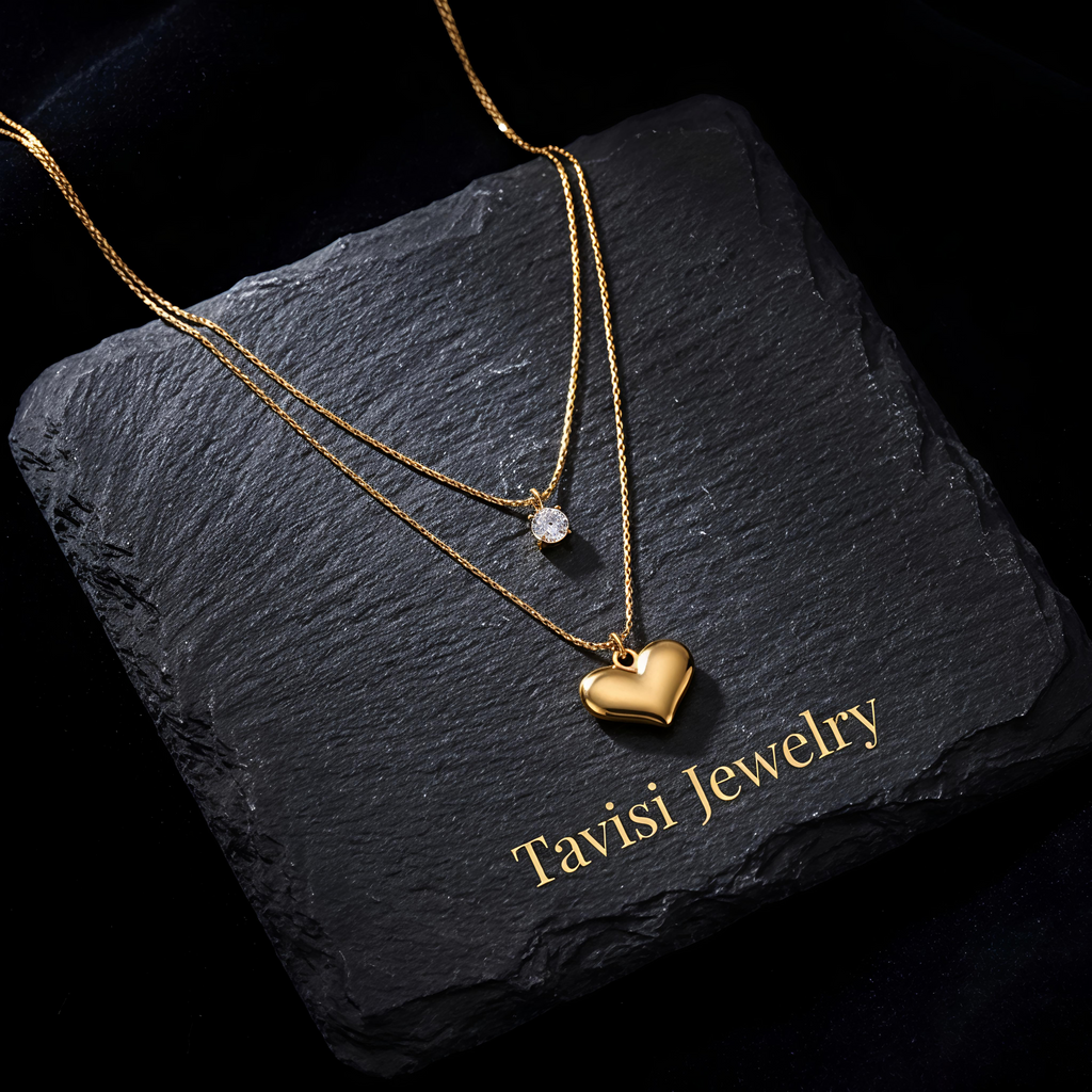 Close-up of Tavisi Amora Dual Layer Necklace showcasing a gold heart pendant and sparkling crystal accent with premium gold plated finish