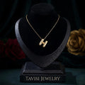 Anti-tarnish gold H pendant necklace displayed on black luxury stand with Tavisi Jewelry branding