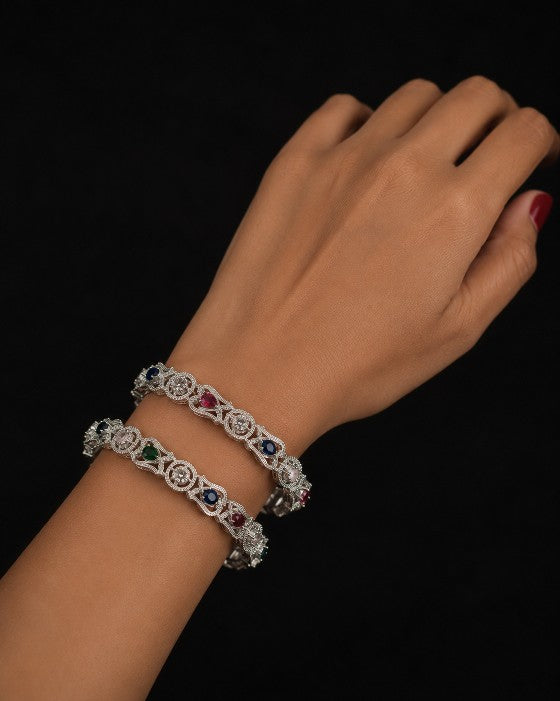 Model wearing Tavisi Color Symphony CZ Silver Polish Bangles featuring sparkling white CZ stones and multicolor AD stones with a premium silver polish finish, available in sizes 2.6 and 2.8.