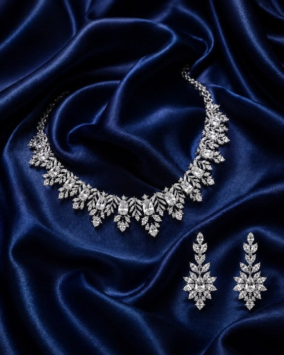 Tavisi Crystal Blossom AD CZ premium brass silver finish necklace set with matching earrings displayed on luxurious blue satin fabric