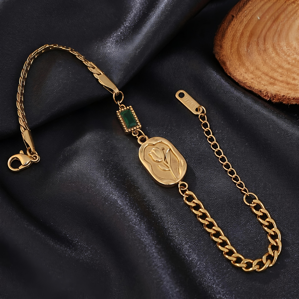 Close-up view of Tavisi Emerald Rose Chain Bracelet featuring an engraved rose motif, green accent detail, premium gold plated stainless steel and anti tarnish finish.