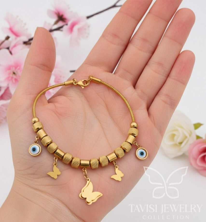 Detailed view of Tavisi Evil Eye Butterfly Charm Bracelet with textured gold beads, butterfly charms, evil eye accents, 22K gold plating and anti tarnish stainless steel construction.