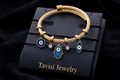 Tavisi Evil Eye Gold Charm Bracelet in 316L surgical stainless steel with 22K gold plated anti tarnish finish, evil eye and hamsa charm detailing, lightweight waterproof adjustable design
