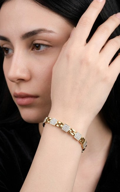 Gold plated stainless steel bracelet with white AD stone links worn on a woman's wrist.