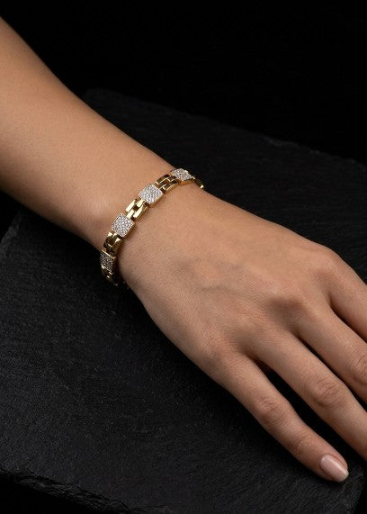 Woman wearing a gold plated stainless steel bracelet with sparkling white AD stone links.