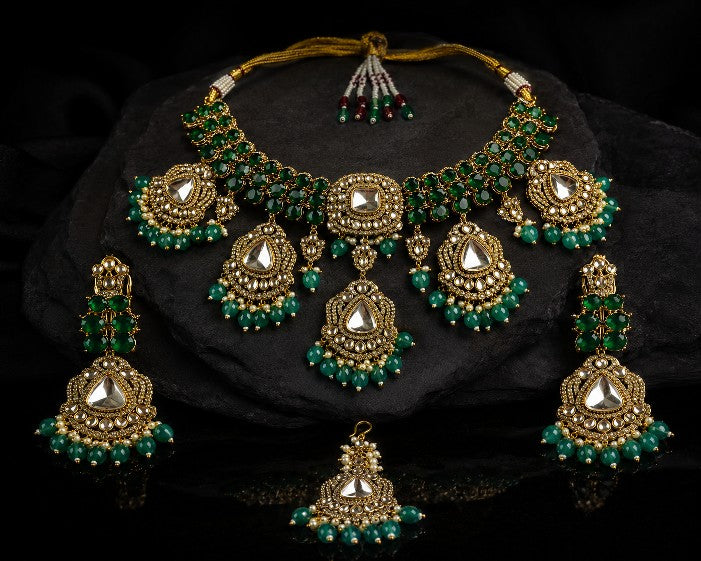 Woman wearing Tavisi Jardin long lasting premium bridal jewellery set with kundan stone, white CZ stones, emerald green AD stones, green beads, white pearls, brass casting and mehanti finish.