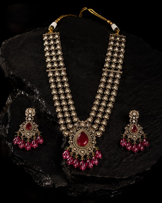 Close-up of Tavisi Ruby Royale layered necklace with white CZ stones, AD detailing, ruby red stones, ruby beads and mehanti color brass casting.
