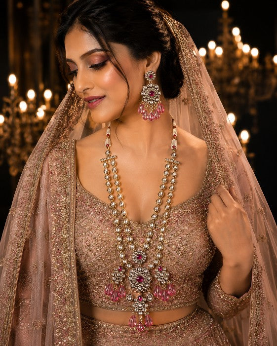 Woman wearing Tavisi Ruby Noir layered bridal necklace set with AD, CZ, ruby pink stones and mehanti finish.