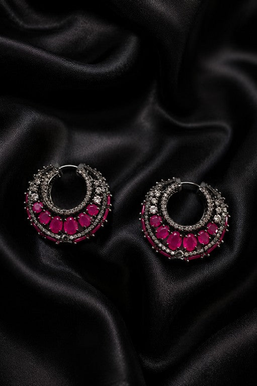 Tavisi Victorian Pink Stone Hoop Earrings with white AD accents and black metal finish displayed on black satin fabric.
