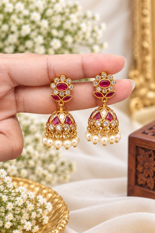 Woman wearing Vallari premium brass floral pearl jhumka earrings with green and pink detailing